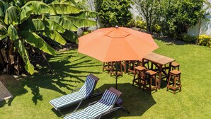 A patio with two lounge chairs, a wooden table, and an orange umbrella. - The best house in cuautla morelos for families and groups of all sizes, (Cuautla)