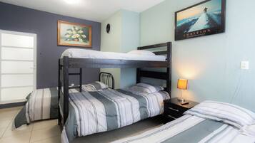 A bunk bed room with a painting, a clock, and a lamp on the nightstand.