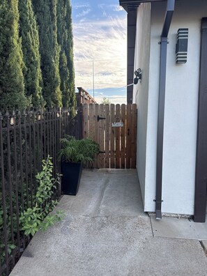 A gated entrance with a wooden fence, a welcome sign, and a potted plant.