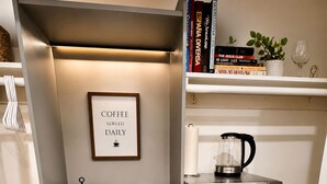 A kitchenette with a coffee maker, a microwave, a small refrigerator, a framed sign, and a shelf with books and a plant. - Cozy Private Suite • Near SMF Airport (Elverta)
