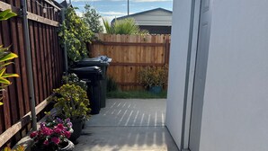 A narrow concrete pathway leading to a garage, flanked by a wooden fence and potted plants. - Cozy Private Suite • Near SMF Airport (Elverta)