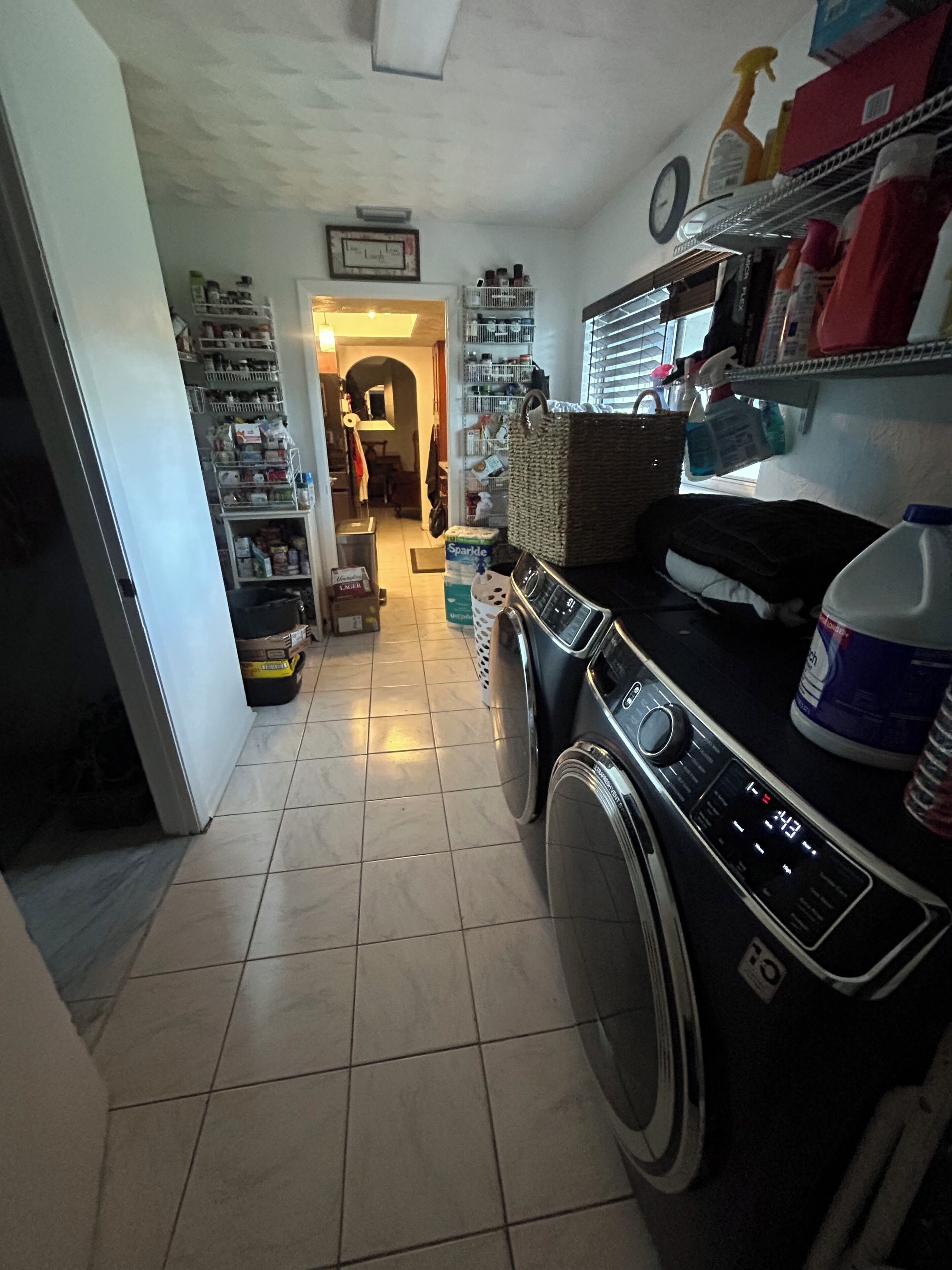 A laundry area with a washing machine, a dryer, and shelves with various items.