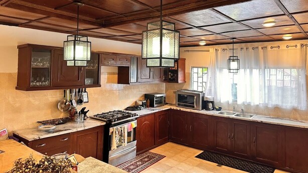 A kitchen with wooden cabinets, a stove, a microwave, and hanging lights.