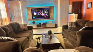 A living room with two sofas, a coffee table, and a flat-screen TV mounted on the wall.