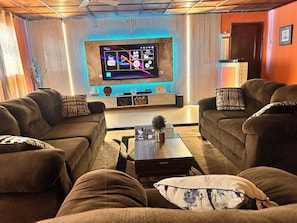 Uma sala de estar com dois sofás, uma mesa de centro e uma TV de tela plana fixada na parede.