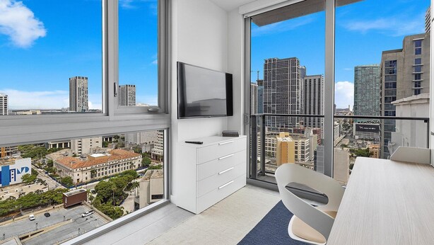 A modern apartment with large windows offering city views, a flat-screen TV, and a minimalist interior. - Premium 2BR Condo | Beautiful City View (Miami)
