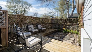 Een houten terras met tuinmeubilair, een pad van stenen en een houten omheining.