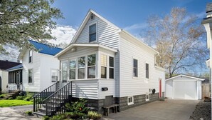Een tweelaags huis met een veranda, een garage en een keurig onderhouden gazon.