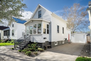 Une maison à deux étages avec un porche à l’avant, un garage et une pelouse bien entretenue.