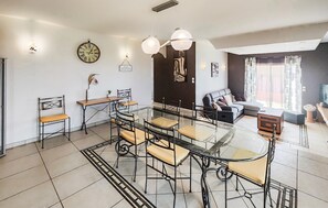 Un soggiorno moderno con un tavolo da pranzo in vetro, un divano e una sveglia appesa al muro.