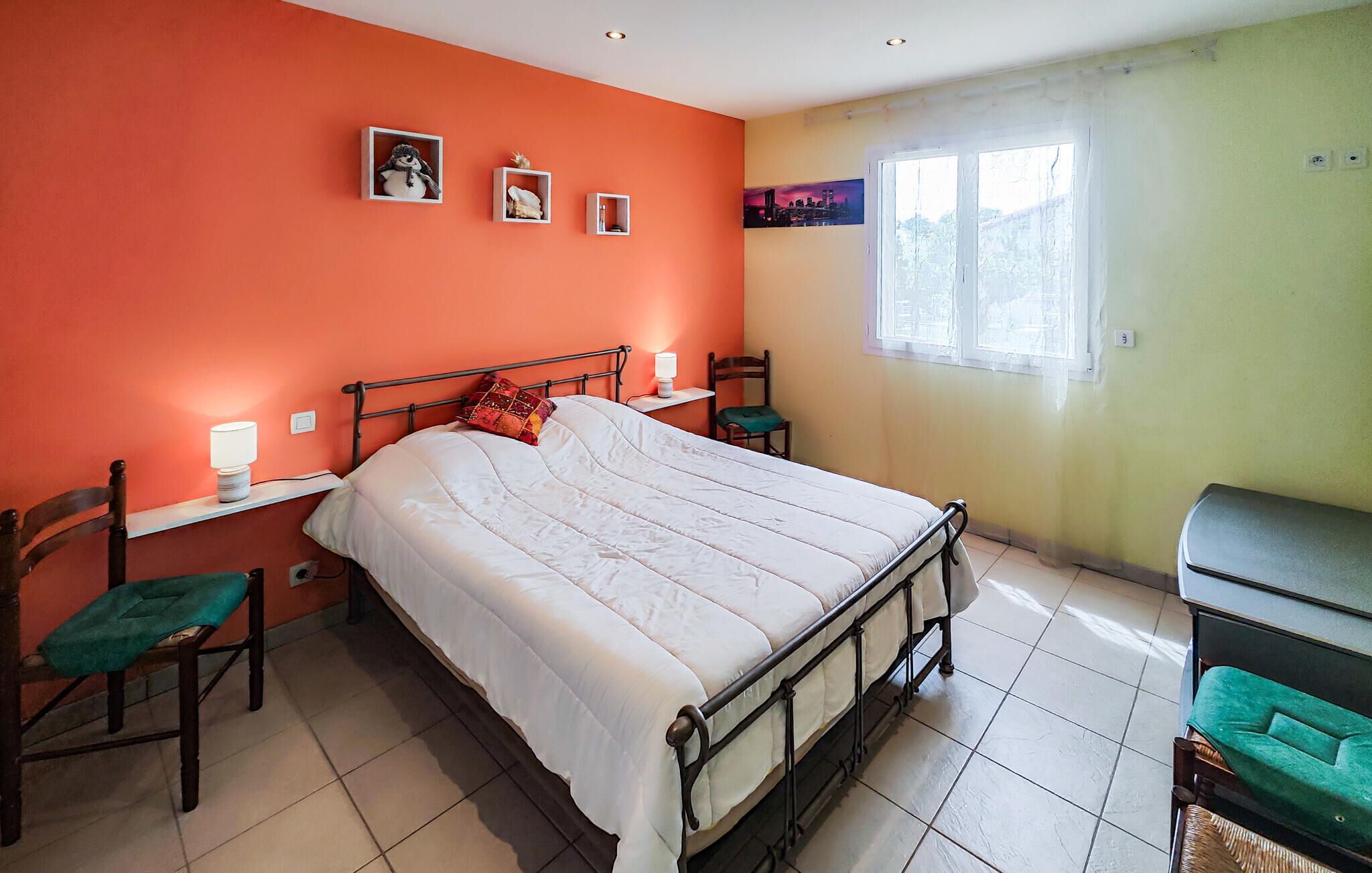 A bedroom with a bed, two chairs, a desk, and a window.