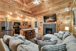 A log cabin interior with a kitchen, living area, and fireplace. - Amazing Getaway Pigeon Forge! Pool/HotTub/FirePit (Sevierville)