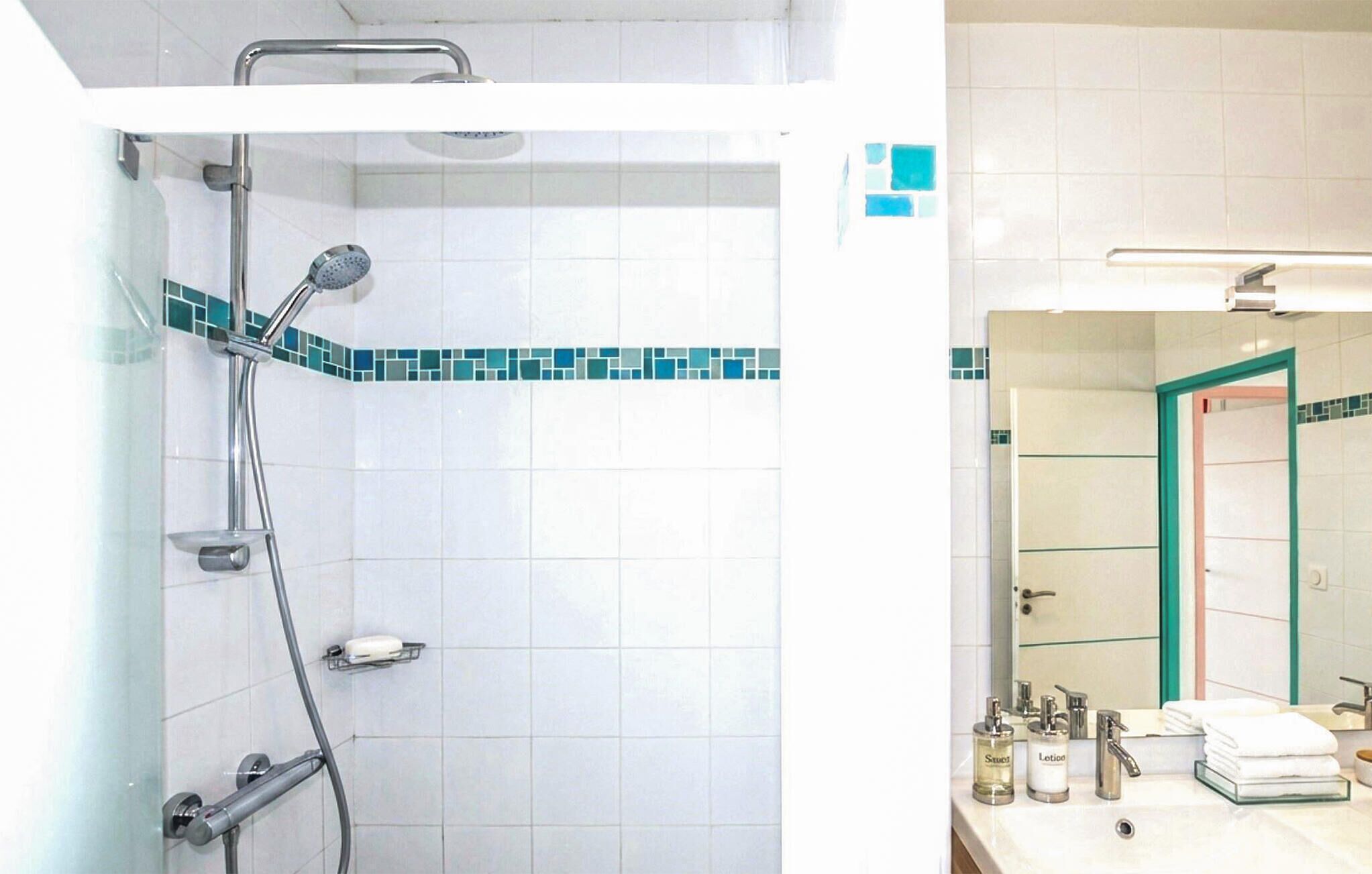 A bathroom with a shower, a sink, and a mirror.