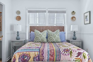 A bedroom with a bed, two bedside tables, a window with blinds, and wall decor. - MarshWalk Apt Near Dining & Beach w/ Free Parking (Murrells Inlet)