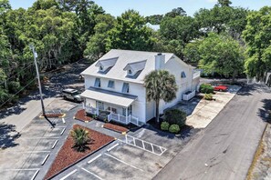 A white two-story house with a gabled roof, a front porch, and a driveway leading to a parking area. - MarshWalk Apt Near Dining & Beach w/ Free Parking (Murrells Inlet)