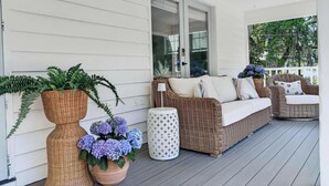 Une véranda avec des meubles en osier, une plante en pot et une petite table.
