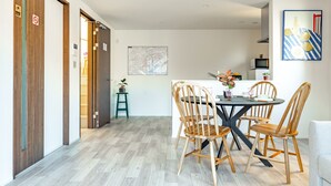 Un coin repas avec une table ronde, des chaises en bois, un petit tabouret et une plante en pot.
