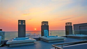 Een dakterras met jacuzzi's en uitzicht op een zonsondergang.