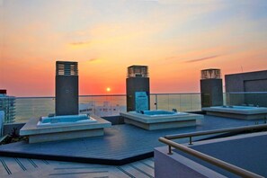 Eine Dachterrasse mit Whirlpools und Blick auf den Sonnenuntergang.