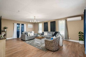 A living room with a grey sofa, a patterned armchair, a coffee table, and a chandelier.