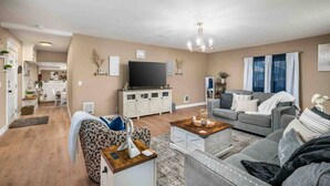 Ein Wohnzimmer mit Sofa, Couchtisch, Fernseher und einem Essbereich mit Tisch und Stühlen.