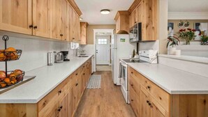 Eine Küche mit Holzschränken, einer weißen Arbeitsplatte, einer Mikrowelle und einem Kühlschrank.