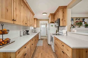 A kitchen with wooden cabinets, a white countertop, a microwave, and a refrigerator.