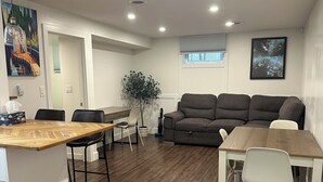 Een moderne woonkamer met een houten eettafel, een grijze bank en een witte stoel.