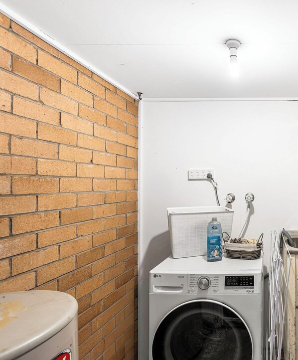 Un cuarto de lavandería con lavadora, secadora y pared de ladrillo.
