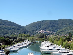 A marina with numerous boats docked along a river, surrounded by lush green hills and a small town in the background. - Mago in Ameglia by Interhome (Ameglia)