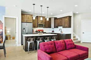 A modern kitchen with dark wooden cabinets, stainless steel appliances, and a central island with bar stools. - Ultimate 10BR 28-Guest Getaway-Zion Area (Hurricane)