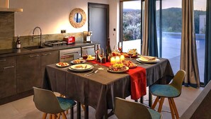 A dining area with a table set for four, a kitchen with modern appliances, and a view of the outdoors. - Stunning home in Mollans-sur-Ouvèze with sauna (Mollans-sur-Ouvèze)