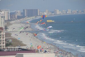 A beach with numerous kites, a pier, and buildings in the background. - Best Views! Penthouse 3BD/3BA Corner Unit w/ Huge Wrap-Around Balcony (Myrtle Beach)