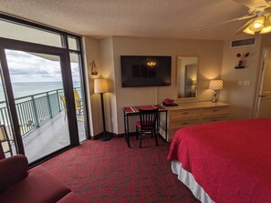 Ein Hotelzimmer mit Bett, Schreibtisch, Stuhl und einem großen Fenster mit Blick auf das Meer.