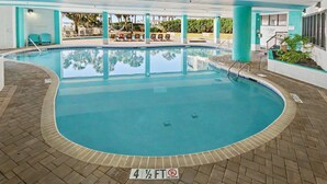 A swimming pool with a depth marker of 4 1/2 feet, surrounded by lounge chairs and a covered area with a view of palm trees. - Oceanfront King Studio w/ Sleeper Sofa + Pools (Myrtle Beach)