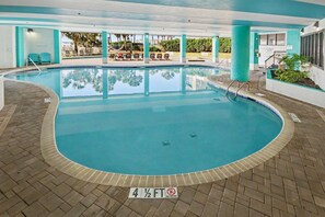 Piscina com indicador de profundidade de 4 pés e meio, cercada por cadeiras de descanso e uma área coberta com vista para palmeiras.