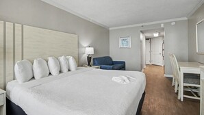 Ein Hotelzimmer mit einem großen Bett, einem Schreibtisch, einem Stuhl, einer Lampe und einem gerahmten Bild an der Wand.