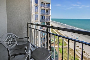 A balcony with a view of a beach and ocean. - Oceanfront King Studio w/ Sleeper Sofa + Pools (Myrtle Beach)