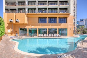 Ein Hotel mit Schwimmbad, mehreren Balkonen und einem Pflasterweg.