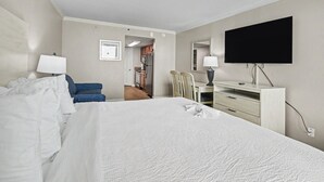 Hotellihuone, jossa on sänky, työpöytä, tuoli, televisio ja kylpyhuone, joka näkyy avoimesta ovesta.