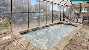 An indoor hot tub with a glass enclosure, surrounded by brick flooring and a metal railing. - Oceanfront King Studio w/ Sleeper Sofa + Pools (Myrtle Beach)