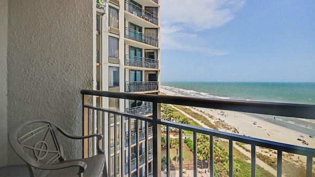 A balcony with a view of the beach and ocean. - Oceanfront King Studio w/ Sleeper Sofa + Pools (Myrtle Beach)