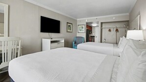 Hotellihuone, jossa on kaksi sänkyä, televisio, työpöytä, tuoli ja vaatekaappi.