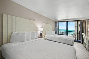 A hotel room with two beds, a balcony with a view of the ocean, and a small table with chairs. - Oceanfront Studio w/ Two Queens + Beach & Pools (Myrtle Beach)