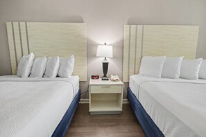 A hotel room with two beds, a nightstand with a lamp, a clock, and a phone. - Oceanfront Studio w/ Two Queens + Beach & Pools (Myrtle Beach)