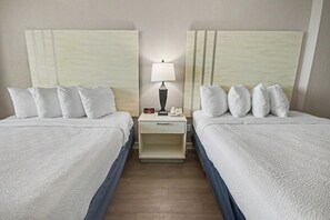 A hotel room with two beds, a nightstand with a lamp, and a small drawer. - Oceanfront Studio w/ Two Queens + Beach & Pools (Myrtle Beach)