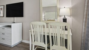 A room with a white desk, a chair, a mirror, a television, and a lamp. - Oceanfront Studio w/ Two Queens + Beach & Pools (Myrtle Beach)