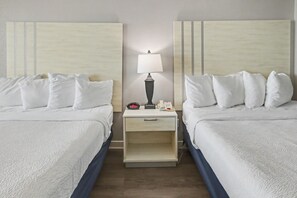 A hotel room with two beds, a nightstand with a lamp, a clock, and a phone. - Oceanfront Studio w/ Two Queens + Beach & Pools (Myrtle Beach)
