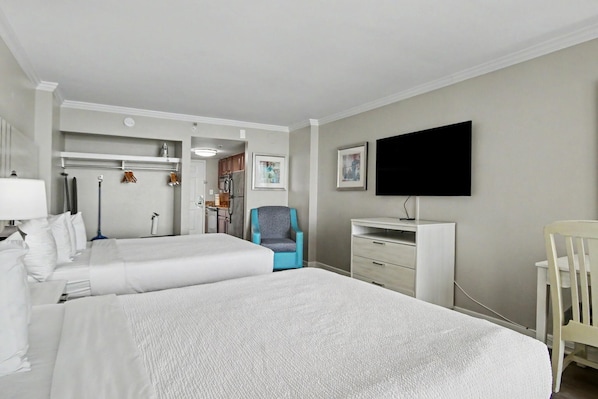 A hotel room with two beds, a desk, a chair, a television, and a wardrobe. - Oceanfront Studio w/ Two Queens + Beach & Pools (Myrtle Beach)
