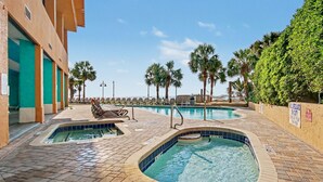 A pool area with multiple pools, lounge chairs, and palm trees. - Oceanfront Studio w/ Two Queens + Beach & Pools (Myrtle Beach)